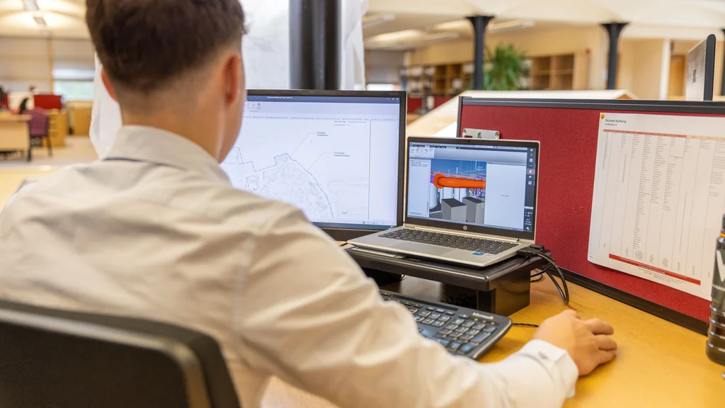 Ingénieur travaillant sur une maquette numérique BIM et un plan de projet dans un bureau d'études